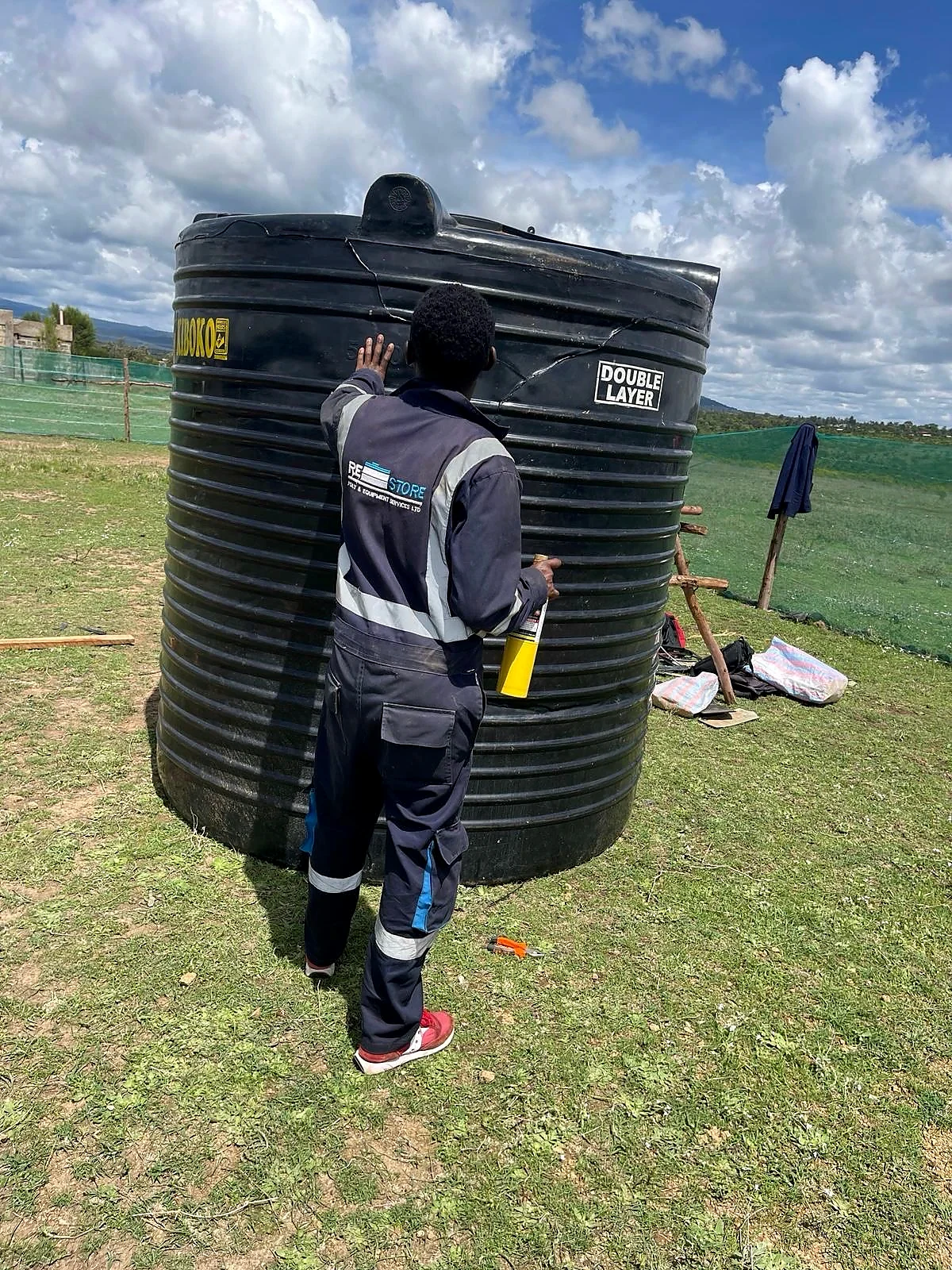 Restore Services technician repairing a large plastic water tank in Kenya