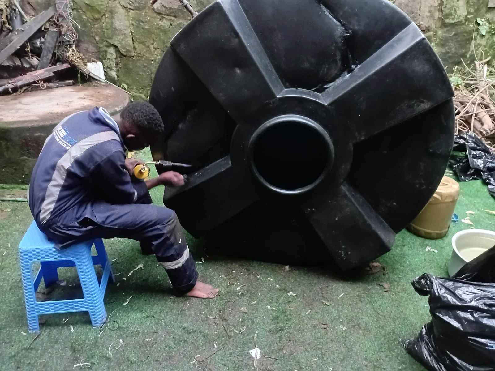 Technician welding a tank base during repair