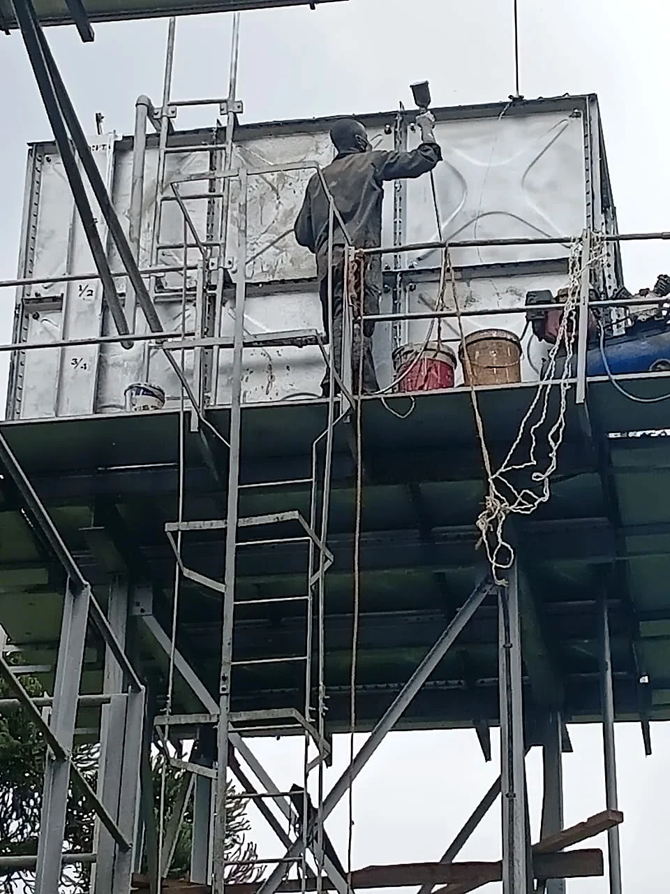 Technician resurfacing and repainting a repaired water tank